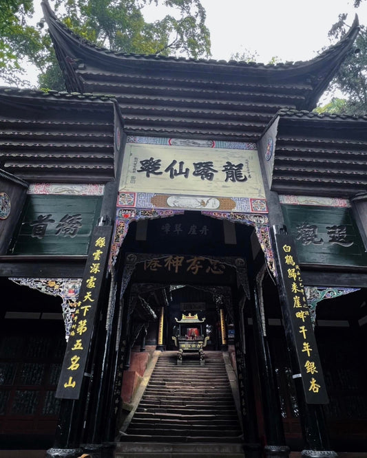 Entrance of a traditional Taoist temple with intricate wooden architecture, a layered roof design, and Chinese calligraphy on plaques and banners, showcasing the cultural and spiritual heritage of Taoism.