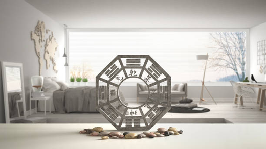 A Feng Shui Bagua mirror placed on a modern minimalist table with natural stones, enhancing harmony in a bright and elegant living space.