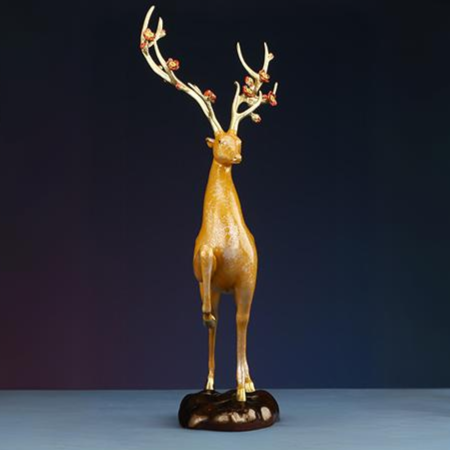 Front view of a golden deer figurine standing gracefully on a polished base.